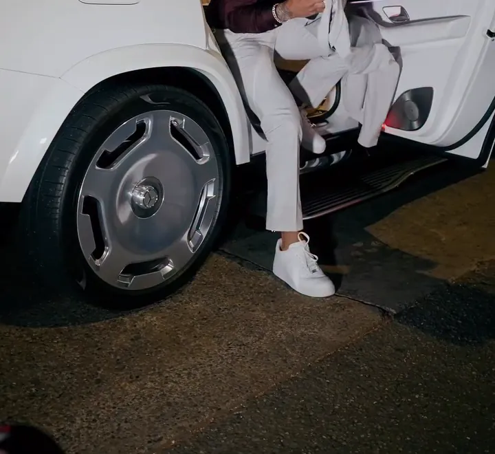 A passenger stepping out of a white Rolls-Royce Cullinan through its rear-hinged door