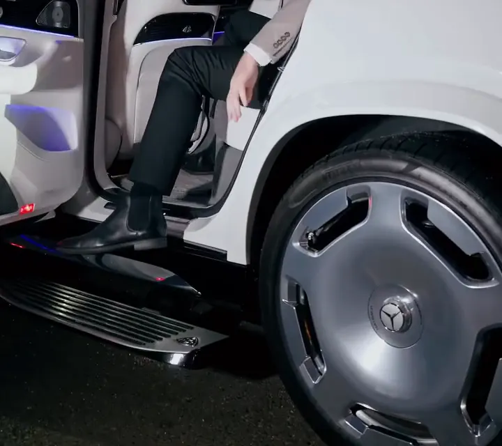 The open rear door, running board and wheel of a white Maybach GLS as a guest steps out