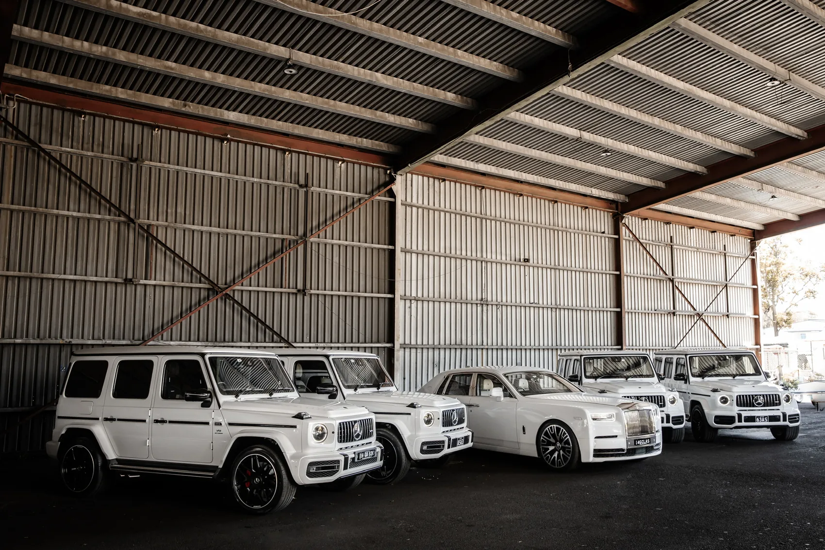 A white Rolls-Royce Phantom flanked by white Mercedes G-Wagons, ready for a wedding
