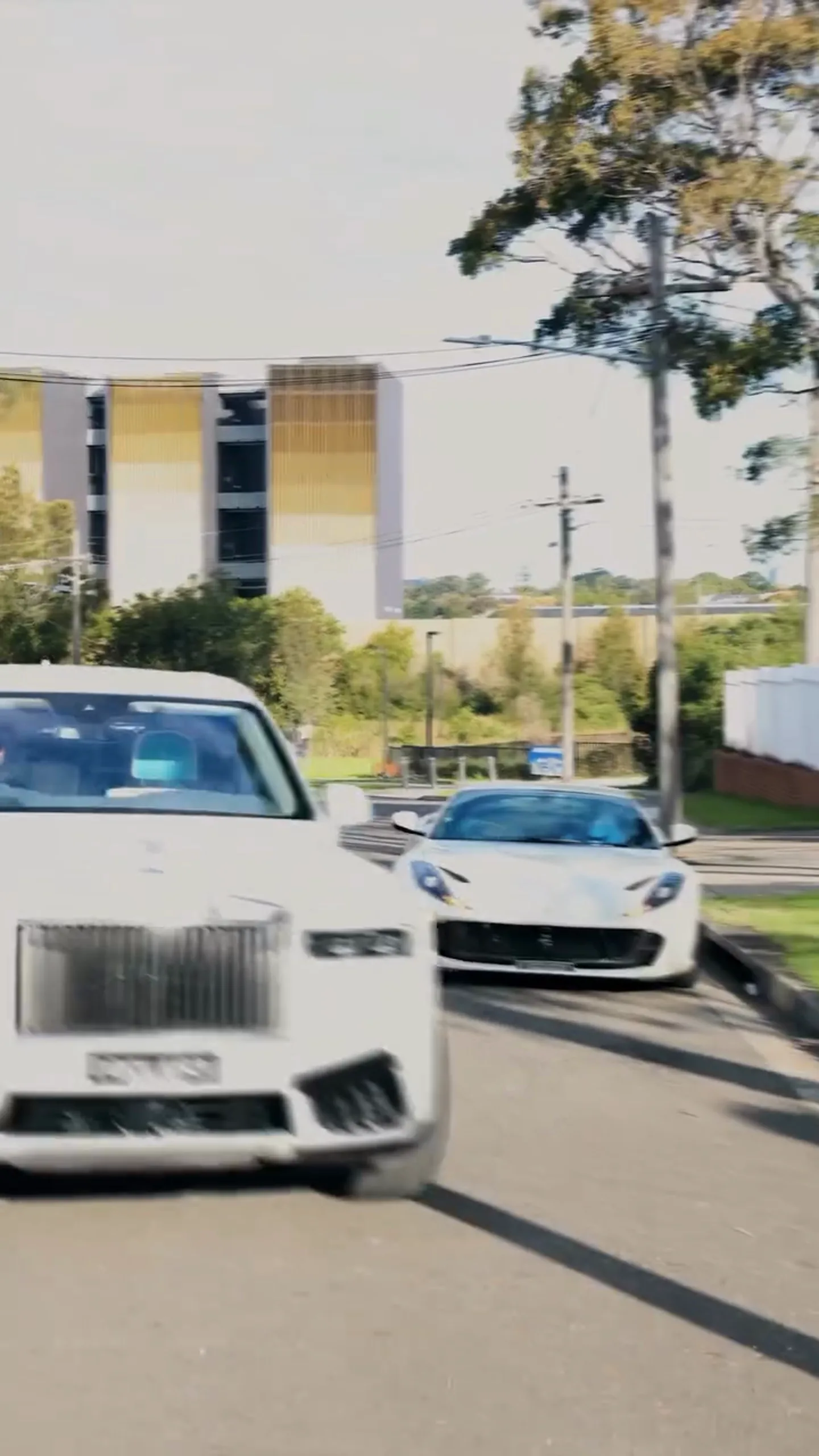 A Rolls-Royce Cullinan towing a Porsche 911 GT3 RS past the Ferrari 812 Superfast on a Sydney street